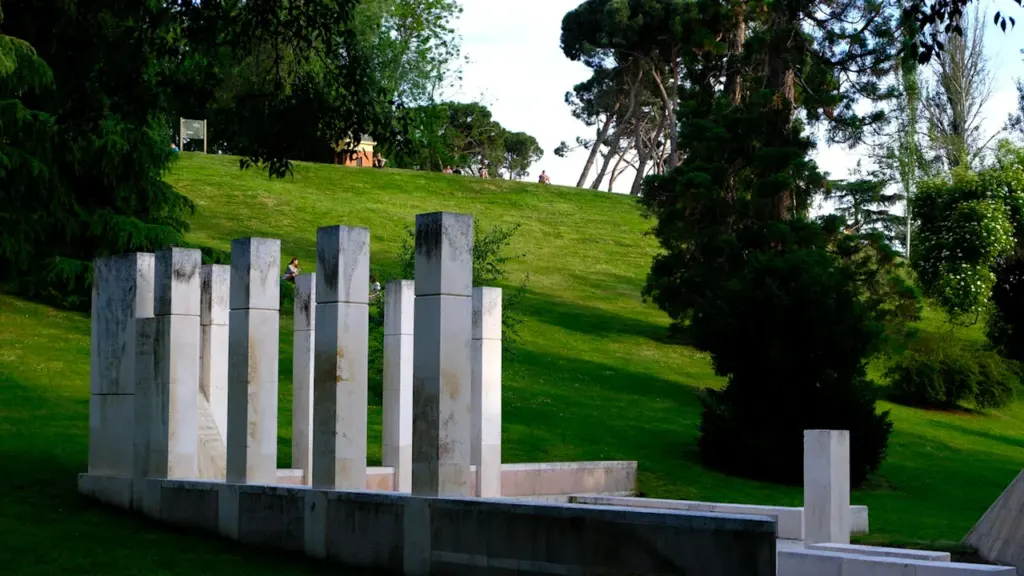 Escultura moderna sobre una colina verde en un parque de Madrid.