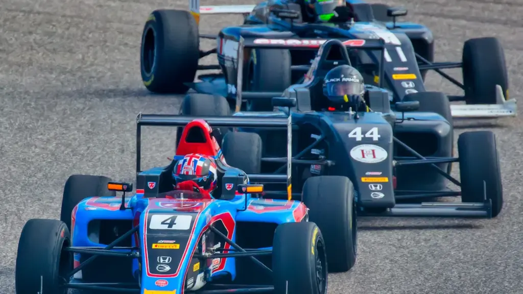 Varios coches de fórmula compitiendo intensamente en la pista durante una carrera automovilística.