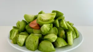 Plato blanco lleno de tomates verdes cortados listos para una receta tradicional andaluza.