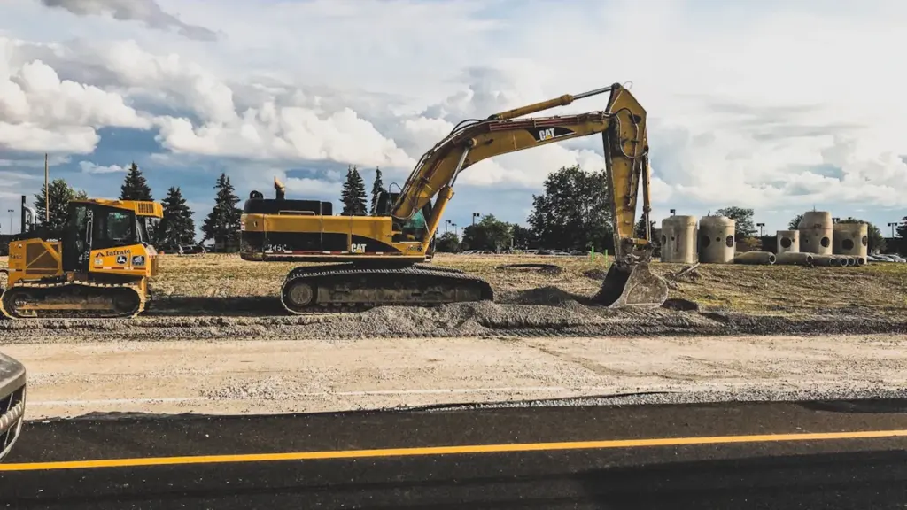 Excavadora amarilla trabajando en el terreno para las obras de seguridad escolar.