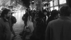 Personas cruzando una calle madrileña iluminada por las luces de la ciudad de noche.