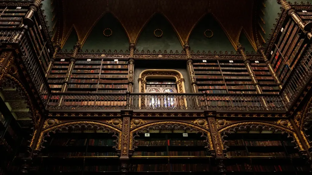 Imponente biblioteca antigua con estanterías de madera ornamentadas y una atmósfera gótica clásica.