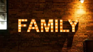 Cartel luminoso con la palabra FAMILY sobre una pared de ladrillos iluminada por la noche.