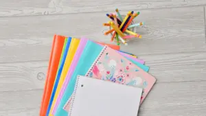 Variedad de cuadernos coloridos y lápices sobre una mesa de madera lista para estudiar.