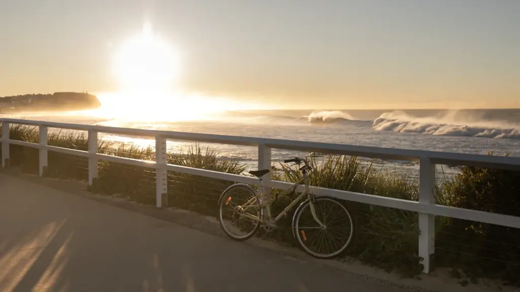 Una bicicleta aparcada junto a la barandilla de un paseo marítimo al atardecer.