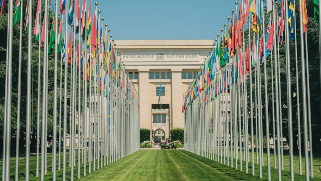 Vista frontal del Palacio de las Naciones de la ONU con banderas internacionales.