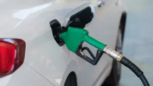 Boquilla de manguera insertada en el depósito de combustible de un coche blanco.