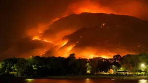 Incendio forestal masivo iluminando la montaña durante la noche en un entorno natural.