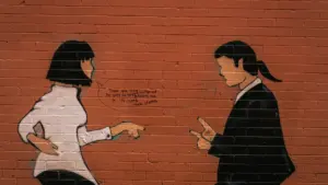 Mural urbano con dos figuras debatiendo, representando diferentes puntos de vista en una pared.