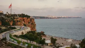 Vista costera de Antalya con acantilados y bandera turca al atardecer.