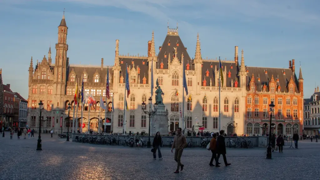 Plaza histórica en Europa con edificios antiguos y una estatua central al atardecer.