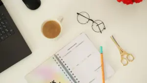 Un escritorio ordenado con agenda, bolígrafo, café y gafas para organizar la semana.