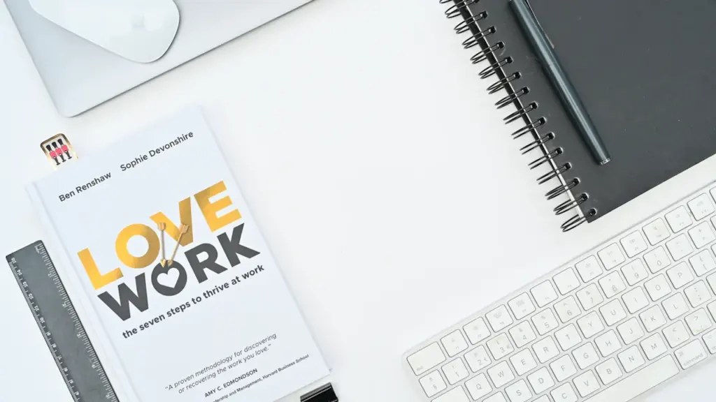 Escritorio de oficina con teclado, ratón y un libro sobre equilibrio laboral.