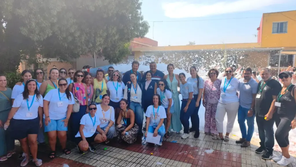 Grupo numeroso de personas posando alegremente al aire libre con espuma festiva de fondo.