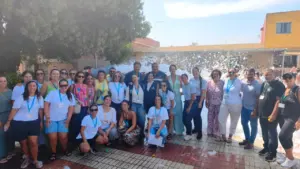 Grupo numeroso de personas posando alegremente al aire libre con espuma festiva de fondo.